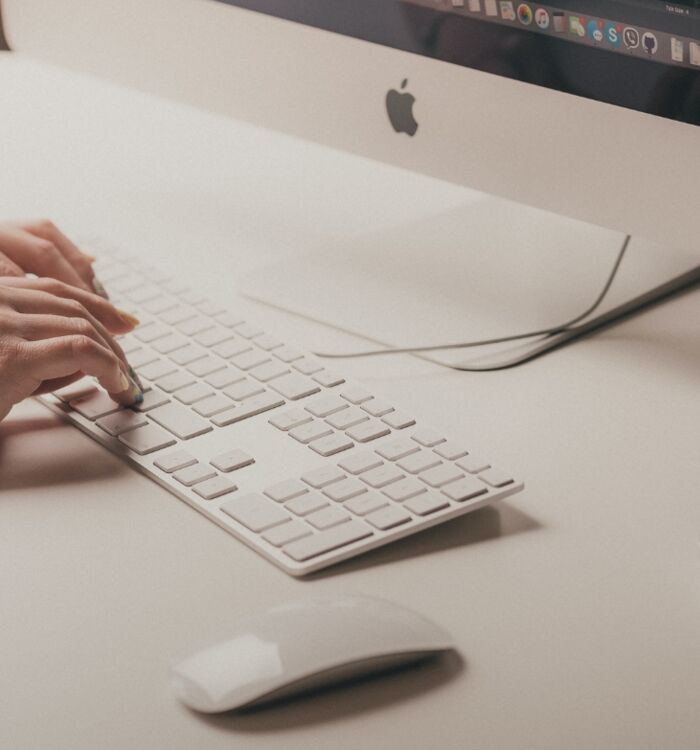 Eine Person schreibt auf die Tastatur eines iMac.